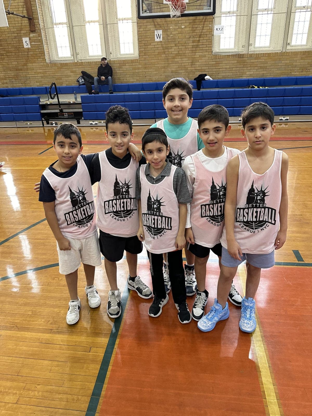 A group of players in pink BBLNYC pinnies standing shoulder to shoulder on the court