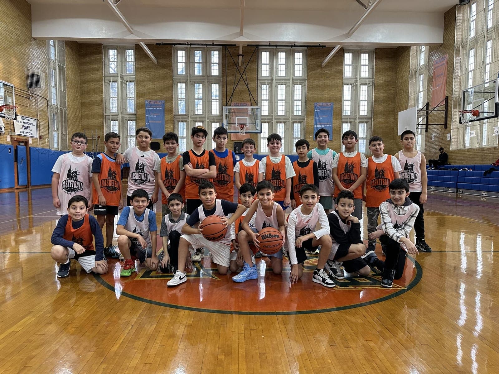 A full session posed at the center circle, front row kneeling with basketballs