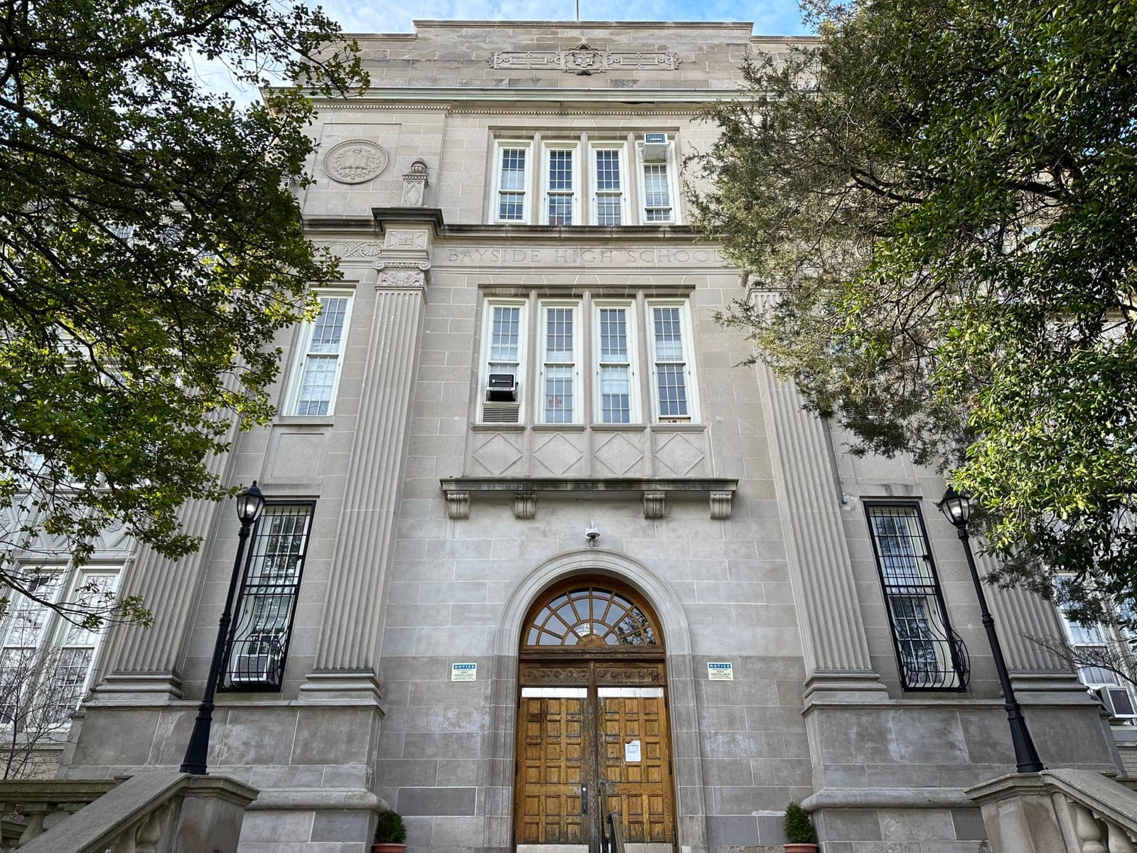 The school's main entrance — a stone facade with an arched wooden door and lamp posts
